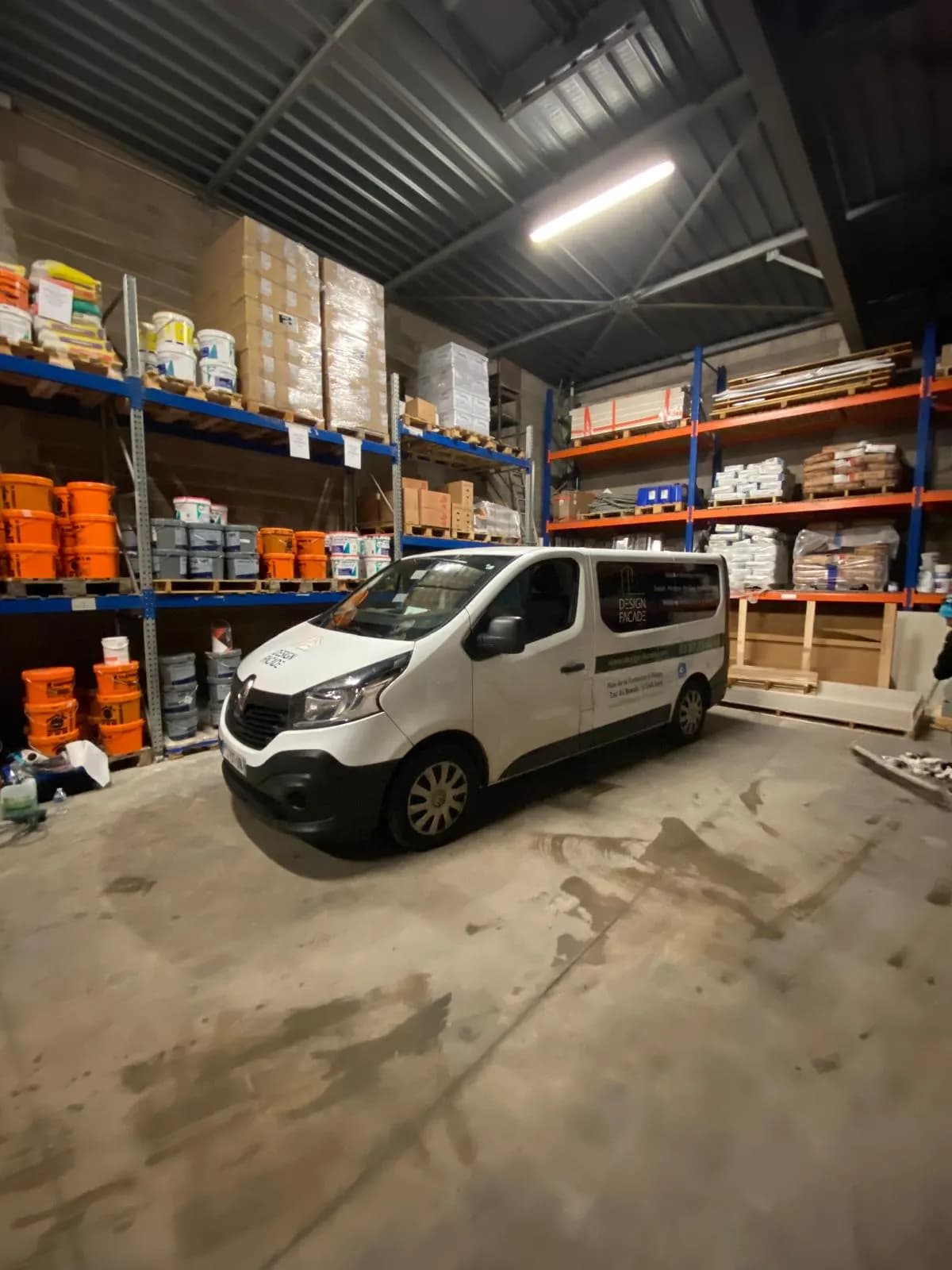 Utilitaire blanc avec lettrage adhésif, stationné dans un entrepôt de matériaux du bâtiment