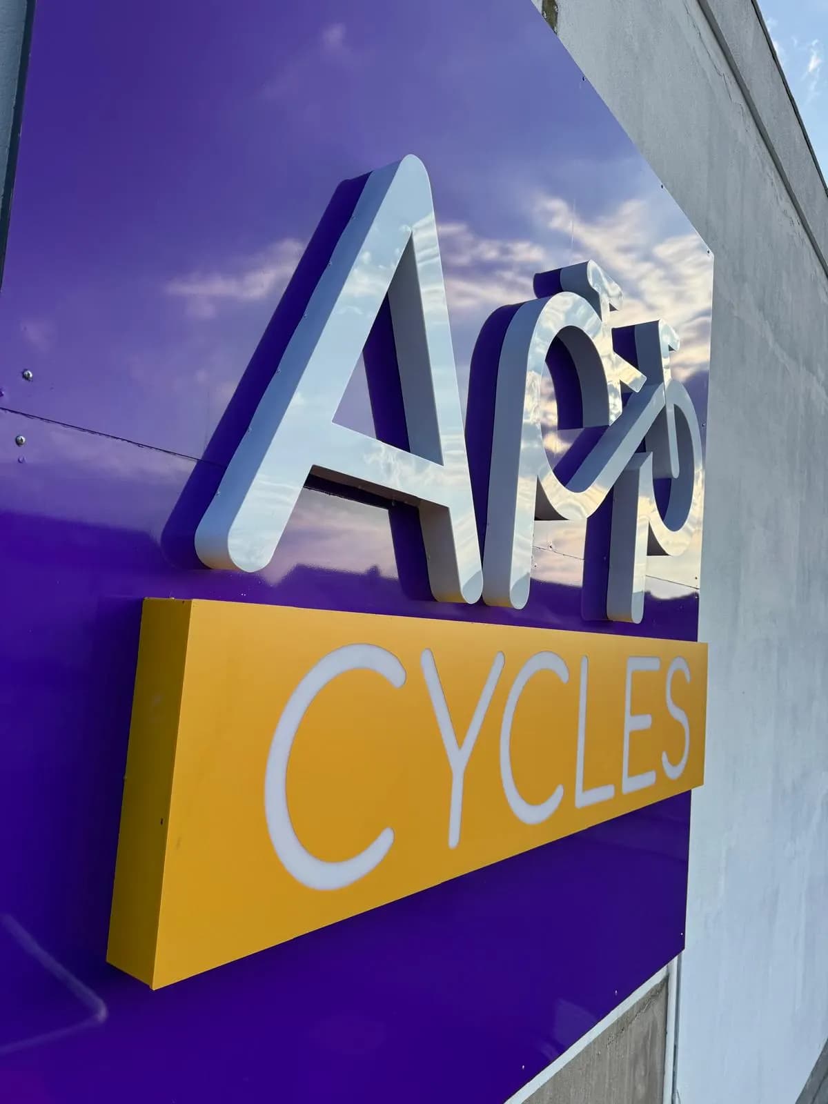 Enseigne de magasin de cycles : lettres relief blanches et caisson jaune sur fond violet